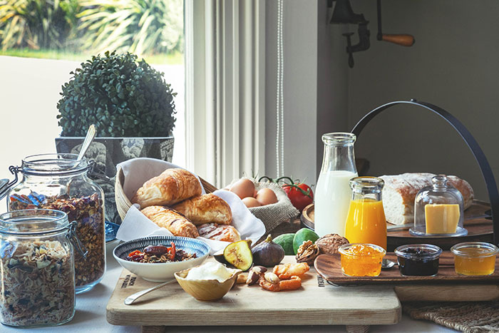 A continental breakfast spread. Includes Croisants, organe juice, milk, jams, fresh bread and muesli