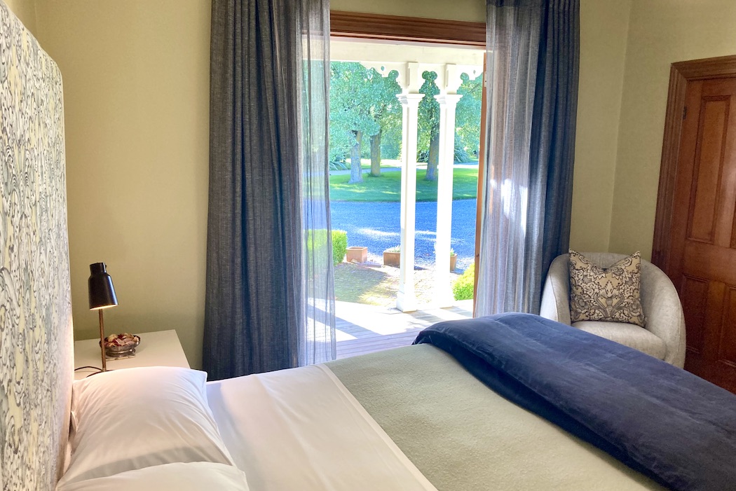 View from the Verandah suite. Looking across the bed out through the open door over a verandah towards large trees